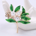 Detalle de un broche floral con hojas de esmalte verde y perlas blancas sobre cerámica - Verde