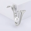 Dettaglio della spilla a sassofono argento con metallo lucido e perla bianca centrale - Argento