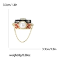 Vintage camera brooch with enamel detail, pearl lens, and decorative gold chain - Gold