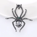 Macro shot of spider brooch with grey crystal body and emerald green rhinestone eyes - Black