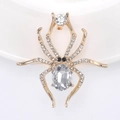 Macro shot of gold spider brooch featuring large oval crystal and pavé rhinestones - Gold