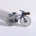 Dettaglio di una spilla a forma di bici vintage con smalto blu e strass scintillanti - Blu