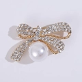 Close-up of golden bow brooch featuring sparkling rhinestones and a large white pearl - Gold