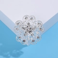 Close-up of a silver floral brooch with hollow heart-shaped petals and sparkling rhinestones - Silver