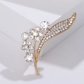 Close-up of elegant gold flower brooch with sparkling rhinestones on white display - Gold