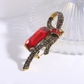 Vista dettagliata di una spilla a fiocco vintage con cristallo rosso e strass grigi su oro - Rosso