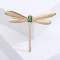 Detailed close-up of golden dragonfly brooch with green gemstone and sparkling crystals - Gold