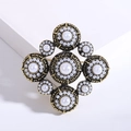 Vintage Baroque brooch in antique gold metal with white pearls on white display stand - Gold