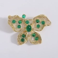 Macro shot of gold butterfly brooch with green gems and cubic zirconia inlay detail - Green-8387