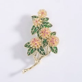 Detailansicht der Brosche mit Zirkonia-Blüten, Goldplattierung und grünen Emaille-Blättern - Gold
