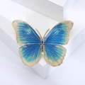Vue détaillée d'une broche papillon en émail bleu avec des bordures dorées élégantes - Bleu