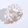 Détail d'une broche couronne papillon dorée avec perles et strass étincelants colorés - Or