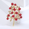 Dettaglio di una spilla a ramo dorato con bacche rosse e strass lucidi su sfondo bianco - Bacca Rossa-Oro (MM-BR-3206)