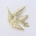Gros plan détaillé d'une broche colibri dorée montrant la texture des plumes - Or