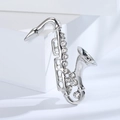 Close-up of silver saxophone brooch with sparkling rhinestones on white display - Silver