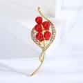Detail van een elegante gouden broche met rode bessen en sprankelende kristallen bladeren - Rood