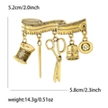 Vintage gold sewing tool brooch with scissors, thimble, and thread pendants on white background - Antique Gold