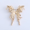 Macro shot of liquid metal butterfly brooch featuring molten gold finish and tassel details - Gold