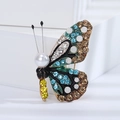 Macro detail of butterfly brooch featuring colorful rhinestones and a white pearl head - Blue