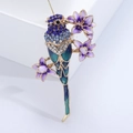 Dettaglio di una spilla a pappagallo colorata con strass e smalto su ramo fiorito - Blu