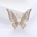 Macro shot of butterfly brooch with rhinestones and white pearl on gold alloy base - Gold