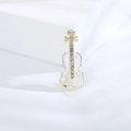 Vista macro di un'elegante spilla a violino dorata con smalto bianco e cristalli - Bianco