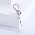 Macro shot of minimalist silver knot brooch with cylindrical drops on white geometric base - Silver