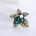Primer plano del broche de hoja dorada vintage con cristal esmeralda y perla - Verde