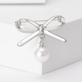 Vista dettagliata di una spilla a fiocco argento con perla bianca su una base bianca - Argento