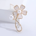 Dettaglio di un'elegante spilla a fiore dorata con petali di perla e foglia di cristallo - Oro