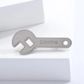 Minimalist silver alloy wrench brooch with engraved creative text on a white pedestal - Silver