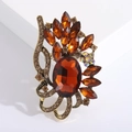 Detail view of a vintage bohemian brooch with amber oval stone and antique gold metal - Brown