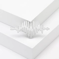 Minimalist silver heart EKG brooch with arrow design on a white geometric platform - Silver