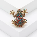 Broche de rana vintage dorado con cristales de colores sobre fondo blanco liso - Colorido