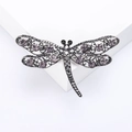 Détail macro de la broche libellule argentée avec des strass violets étincelants - Noir