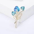 Macro dettagliata della spilla a bouquet con cristalli a cuore blu e strass micro-pave - Base Oro Blu