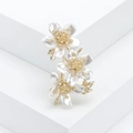 Dettaglio di elegante spilla a fiore dorata con petali bianchi e zirconi lucenti - Oro