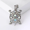 Broche de tortuga vintage plateado con brillantes cristales AB sobre un pedestal blanco - Plateado