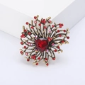 Close-up of vintage gold flower brooch with red crystal stones on a white background - Red