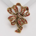 Elegante vintage gouden strikbroche met rode strass-steentjes op een witte display - Rood (MM-BR-3669-RD)