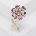 Primer plano de un elegante broche de flor de cristal púrpura con baño de oro y circonitas - Morado