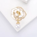 Détail macro d'une broche camélia aux pétales dorés et accent de perle blanche - Doré