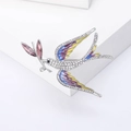 Elegant swallow brooch with colorful enamel wings and sparkling crystals on a white pedestal - Purple