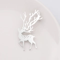 Detailed view of silver deer brooch with cutout spots on a white ceramic plate - Silver
