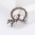 Broche nœud vintage dorée avec perles et strass gris sur un support blanc pur - Or Ancien Strass Noir