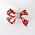 Vista detallada de un broche de lazo en esmalte rojo con lunares blancos y diamantes - Rojo