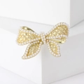 Elegante broche de lazo dorado con textura acolchada y perlas en base blanca - Dorado
