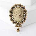 Detail einer Vintage-Kamee-Brosche mit bernsteinfarbenen Strasssteinen und Porträtrelief - Gold