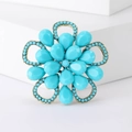 Dettaglio di una spilla vintage turchese e oro con motivo floreale stile boho - Blu