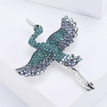 Elegante spilla a forma di gru in argento con cristalli blu e verdi su piedistallo bianco - Blu